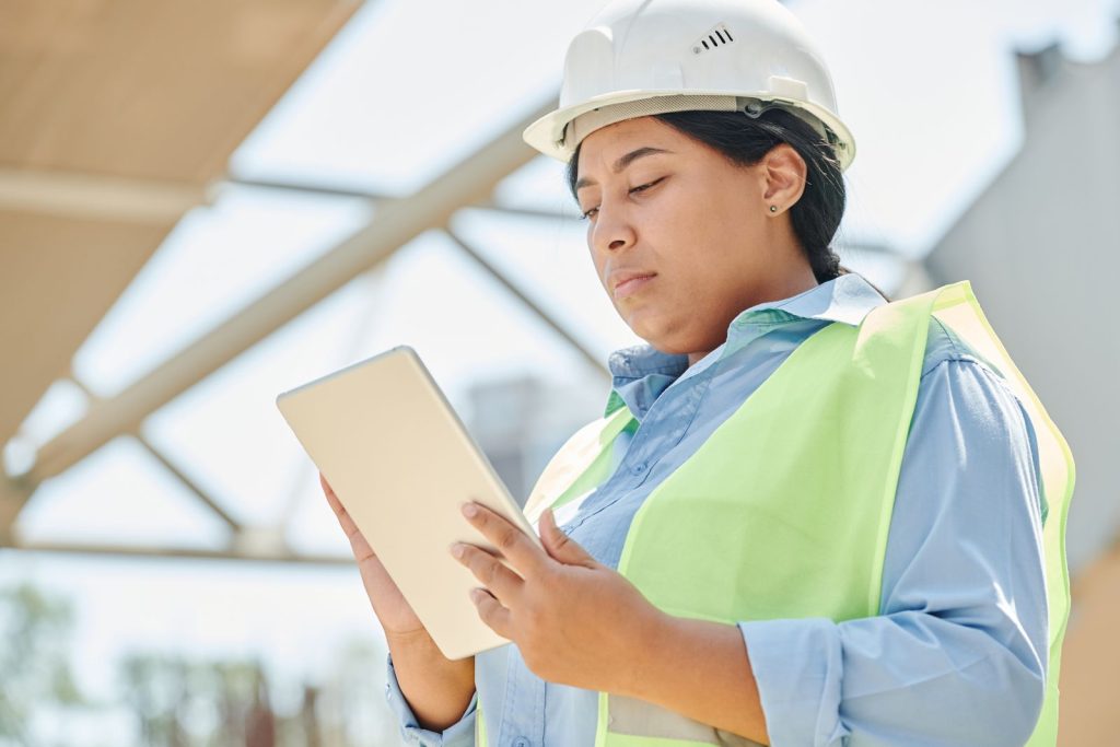Cheffe de chantier en casque consultant son logiciel de gestion sur une tablette