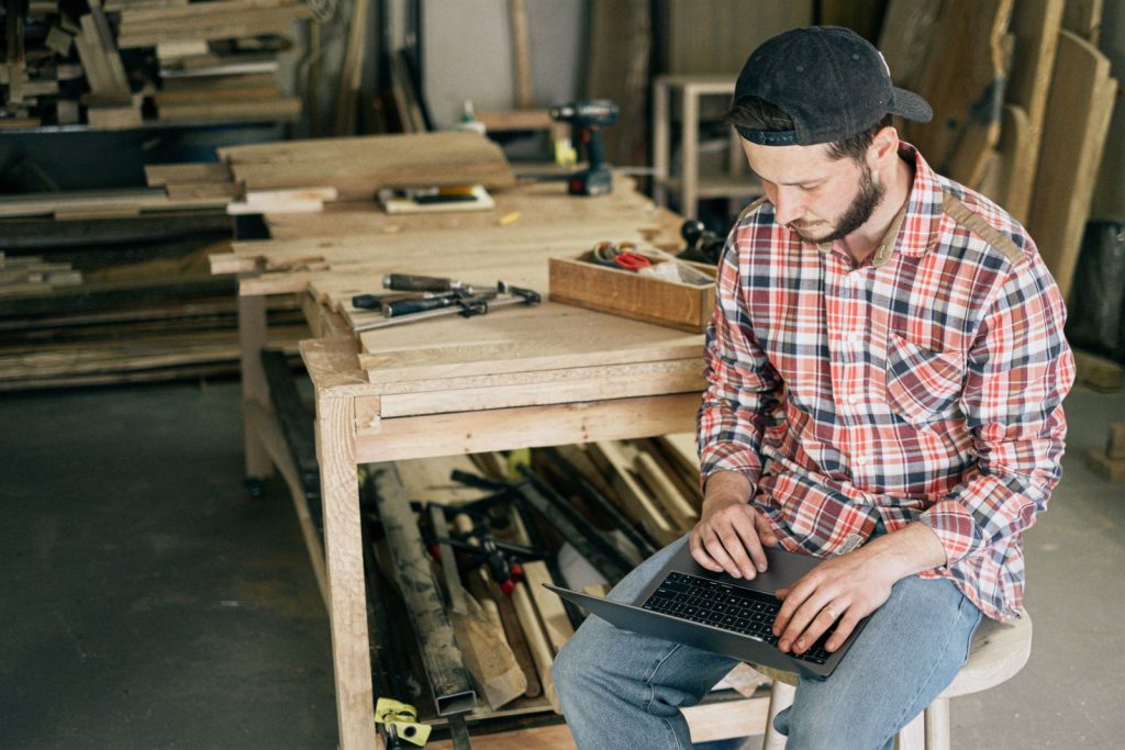 Artisan menuisier consultant un ordinateur portable dans son atelier