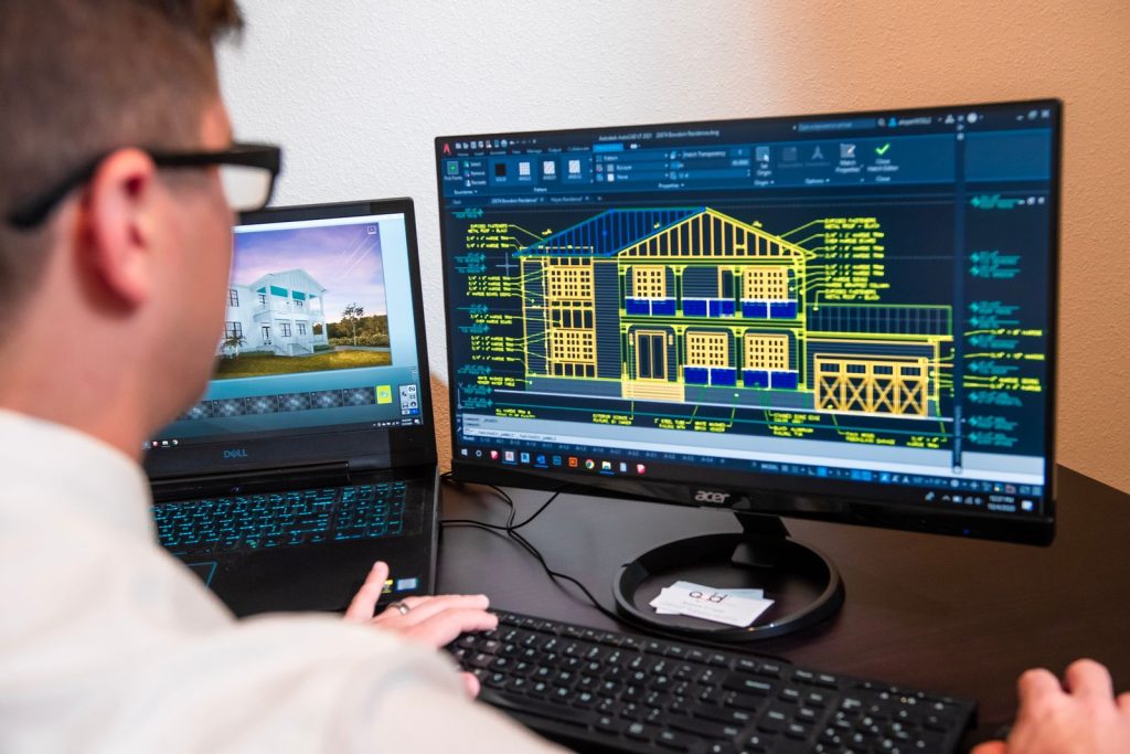 Professionnel du bâtiment travaillant sur des plans de maison affichés sur un écran d’ordinateur