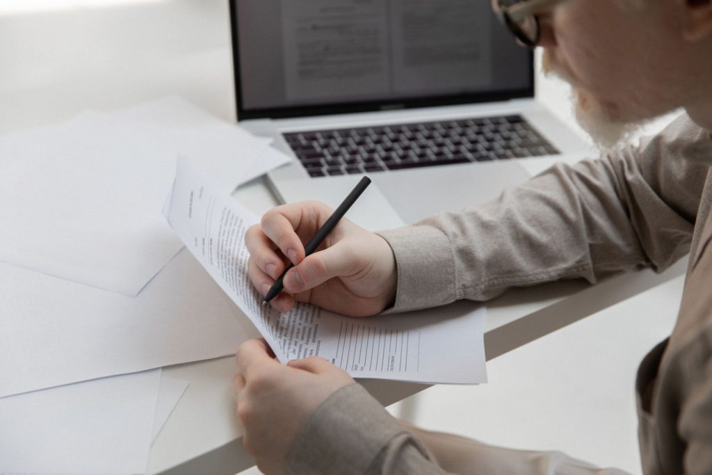 Dirigeant d’entreprise relisant des documents comptables devant son ordinateur portable