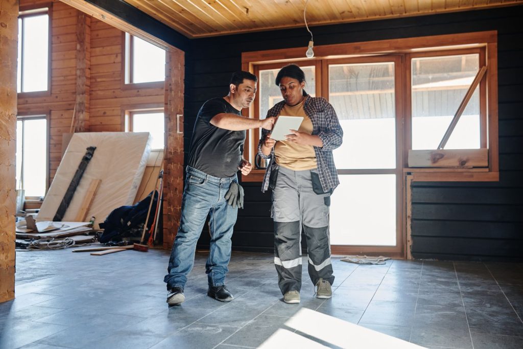 Deux artisans consultent une tablette dans une maison en rénovation pour suivre l’avancement du chantier